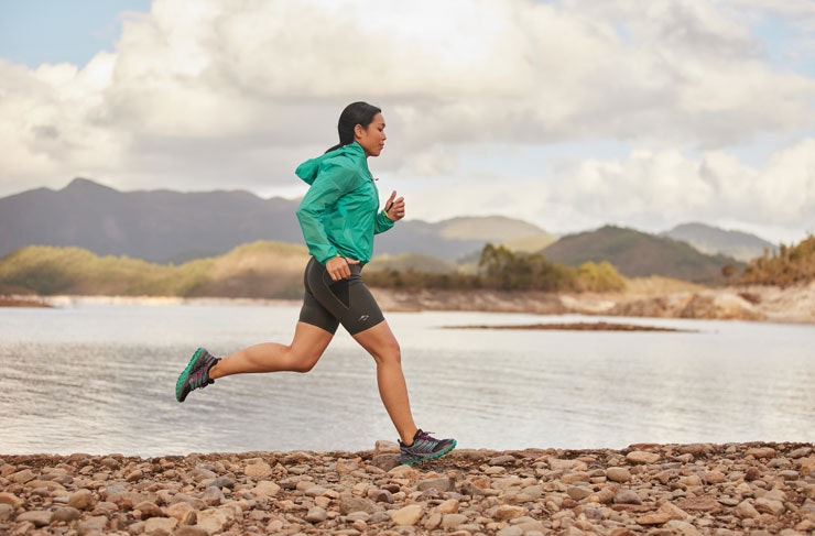 A woman running beside a river.